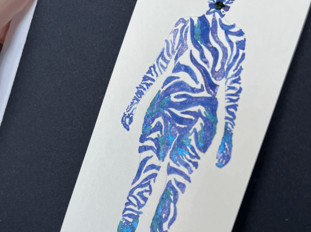 this close up is on the hips and hands. within the zebra white space the green/blue shimmering ink makes small thin lines resembling skin stretch marks and other scarring shapes