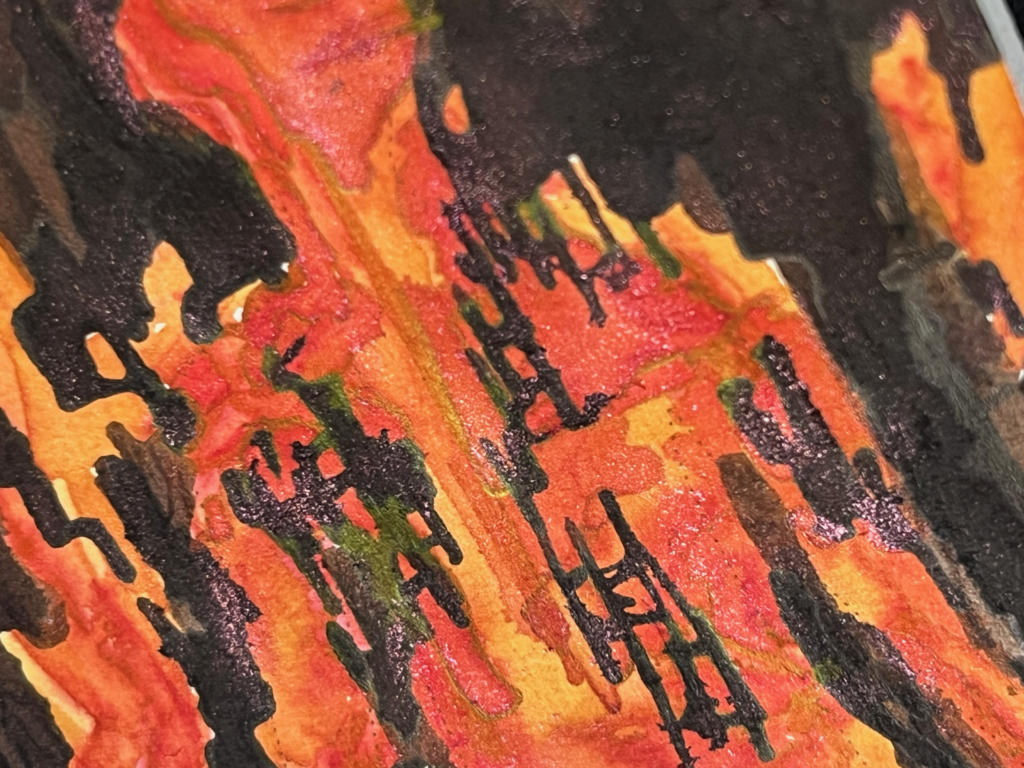 close up of the bookmark, on the figure's chest, showing golden metallic reflections in the ink and reddish pink sparkling embers